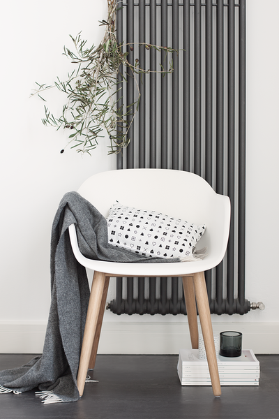 graue heizung vor weißem designerstuhl